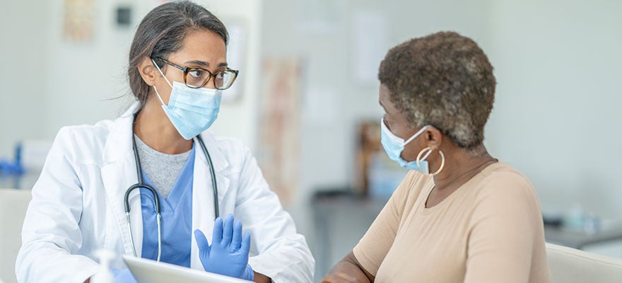 Doctor consults with patient in office visit.