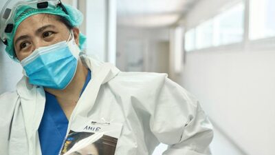 Health care provider wearing full personal protective equipment takes a rest