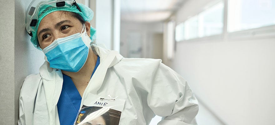 Health care provider wearing full personal protective equipment takes a rest