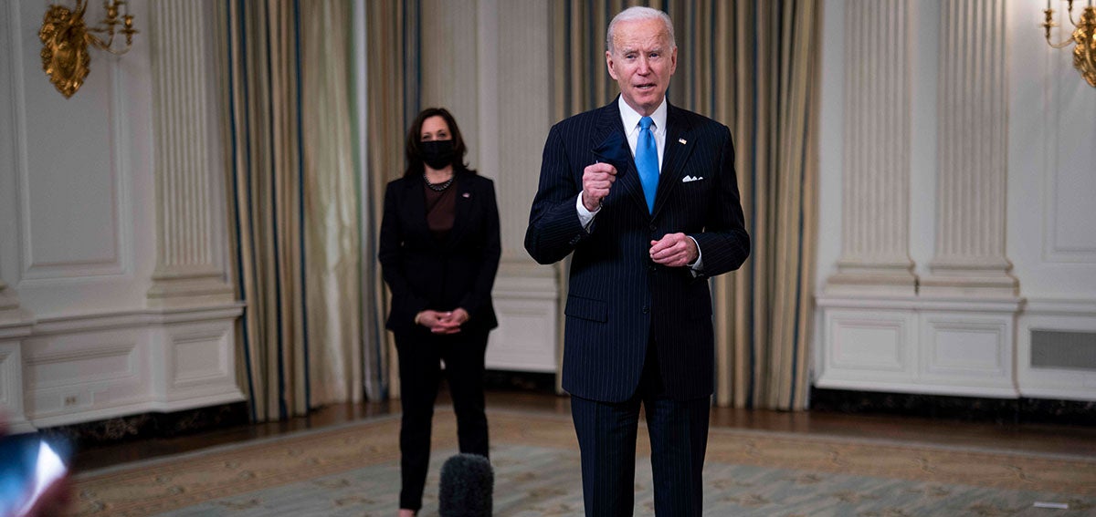 United States President Joe Biden listens to a reporter's question. US Vice President Kamala Harris stands in the background.