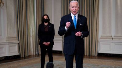 United States President Joe Biden listens to a reporter's question. US Vice President Kamala Harris stands in the background.