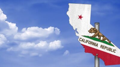 Signpost with a cutout of the state of California and the California flag on it