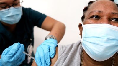 Lorraine Harvey, an in-home care worker, receives her first dose of the COVID-19 vaccine.
