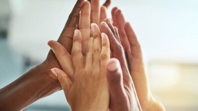 Close up of a group of people's hands giving a high five.