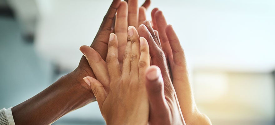 Close up of a group of people's hands giving a high five.