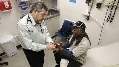 Doctor Leonid Basovich, left, examines patient Michael Epps who has medical insurance coverage through Medi-Cal