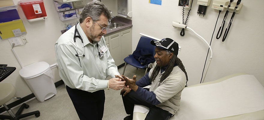 Doctor Leonid Basovich, left, examines patient Michael Epps who has medical insurance coverage through Medi-Cal