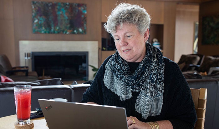 Santa Cruz County Health Officer Dr. Gail Newel sitting at a table, working on a laptop.