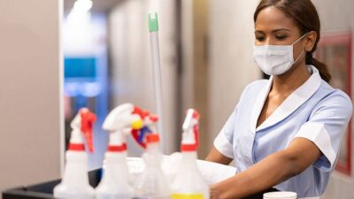 Housekeeper at a hotel with a cart full of cleaning products