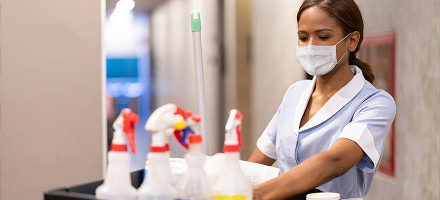 Housekeeper at a hotel with a cart full of cleaning products