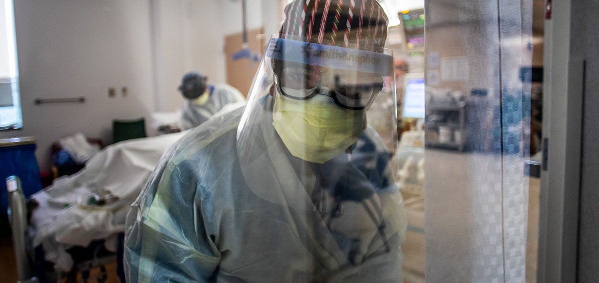 A nurse wearing personal protective equipment (PPE) speaks to a colleagues from inside an Intensive Care Unit (ICU)