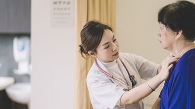 Asian doctor examines elderly Asian woman