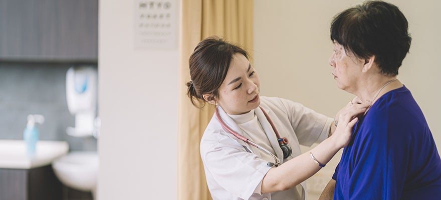 Asian doctor examines elderly Asian woman