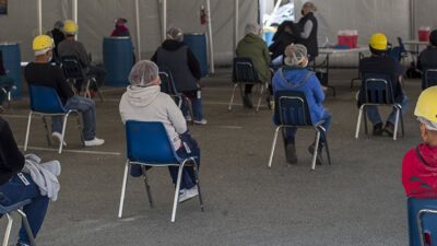 Farmworkers wait after receiving a dose of the Moderna Covid-19 vaccine at a vaccination clinic