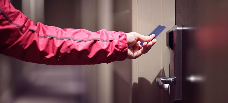 person preparing to insert key card into hotel room lock