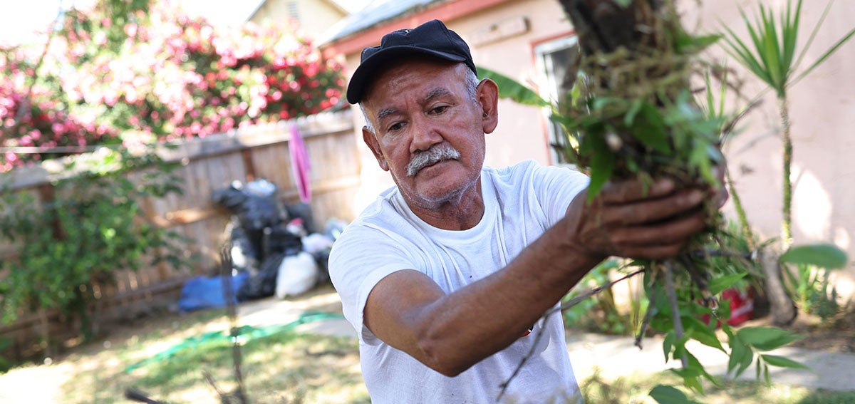 suncion Ponce, a farm worker originally from Puebla, Mexico, cleans up his yard on May 17, 2021 in Fresno, California.