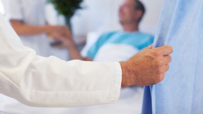 Doctor's hand pulls back hospital curtain.