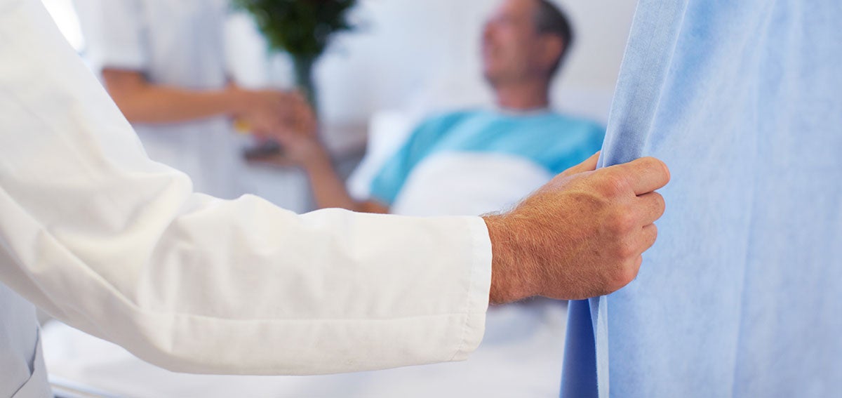 Doctor's hand pulls back hospital curtain.