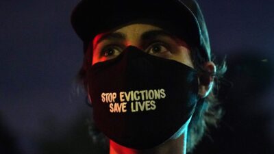 Woman wearing mask that reads "Stop Evictions, Save Lives"