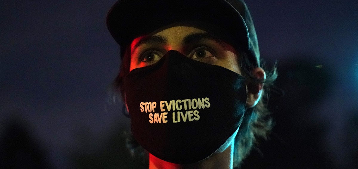 Woman wearing mask that reads "Stop Evictions, Save Lives"