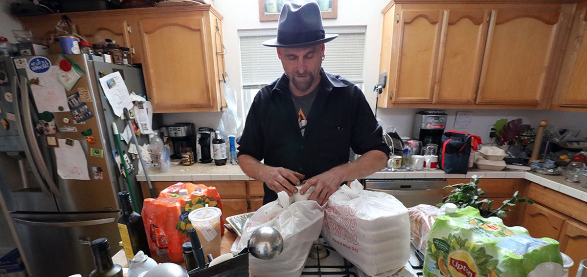 Man unpacks prepared meals in kitchen