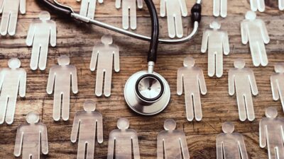 plastic icons of people laying on table with stethoscope