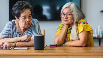 Elderly woman and caregiver learn how to operate smart speaker