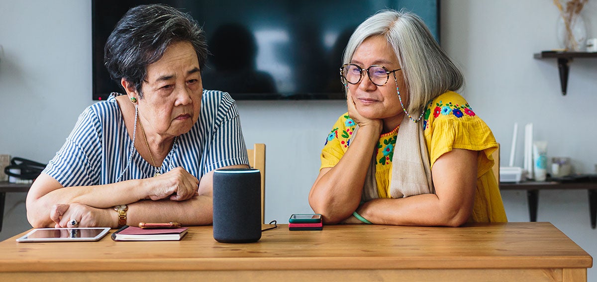 Elderly woman and caregiver learn how to operate smart speaker
