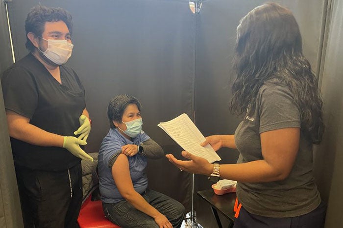 Young boy gets vaccinated by nurse at Kern Medical, father watches.