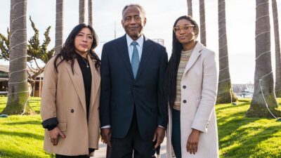 Rowena Robles, Coyness L. Ennix, Jr., and Sequoia Hall standing together at waterfront