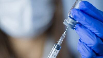 Practitioner draws vaccine from vial into syringe.