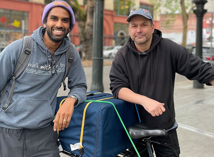 Jonathan Kumar sands with friend next to bike