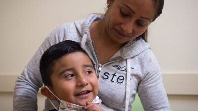 Mother helps son with face mask