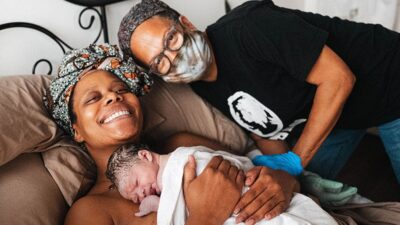 Midwife Kimberly Durdin smiling with second time mom after the birth of her baby at Kindred Space LA Birth Center in South Los Angeles.