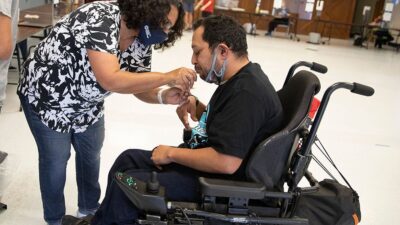 Woman helping man in wheel chair complete medical test