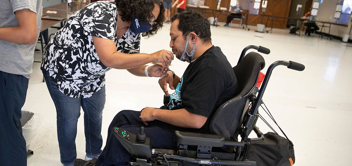 Woman helping man in wheel chair complete medical test