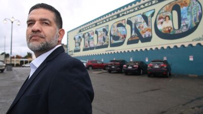 Joe Prado standing in front of "Fresno" mural
