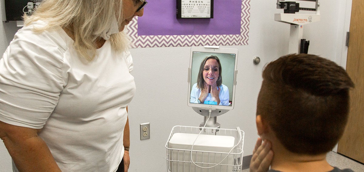 Young patient having an e-visit with doctor while nurse observes.