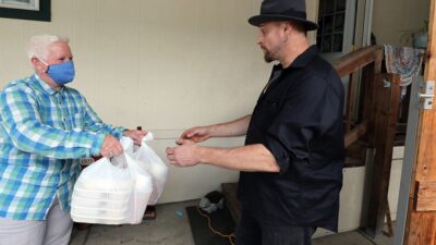 Volunteer delivers medically tailored meal to patient's home.
