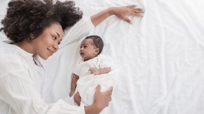 Mother lays on bed with newborn baby.