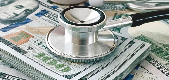 stethoscope resting on a stack of one hundred dollar bills