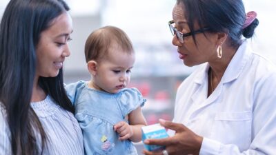 Mother holds baby while talking to doctor about medicine