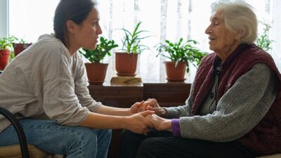 Younger woman assists older woman at home