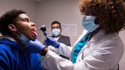 Doctor examines young patients throat.
