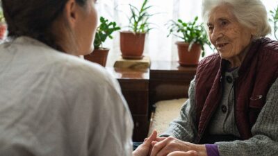 In-home helper talks with elderly woman.