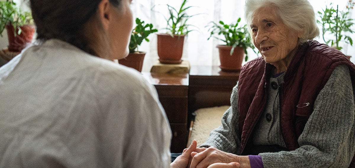 In-home helper talks with elderly woman.