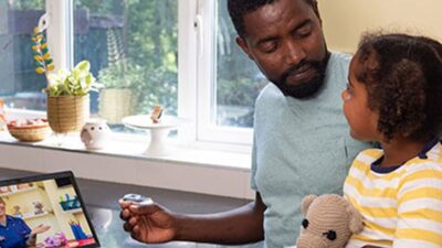 Father and daughter talk to doctor via telehealth visit.