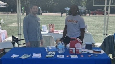 Photo of SCAN Health Plan staff at a health and vaccination info table during a community outreach event in Compton, CA in 2023.