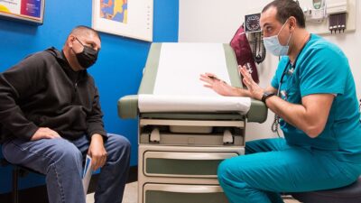Patient and health care provide talk in clinic exam room.