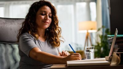Woman sitting at desk with computer and writing materials